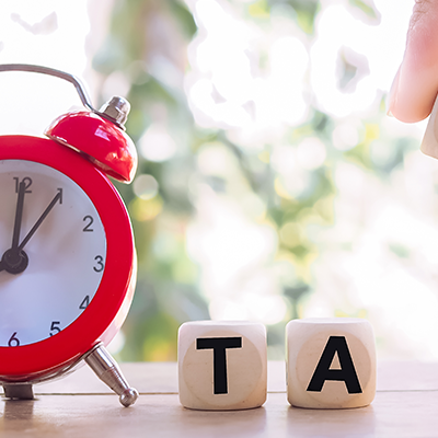 Red alarm and wooden blocks with the word TAX.