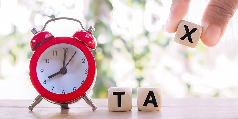 Red alarm and wooden blocks with the word TAX.